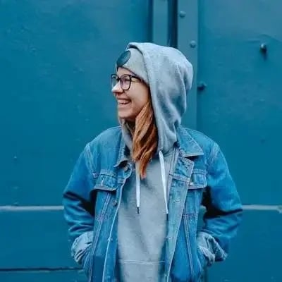 Porträt einer Frau in Jeansjacke vor einer blauen Wand