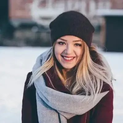 Porträt einer lächelnden Frau mit Mütze und Schal